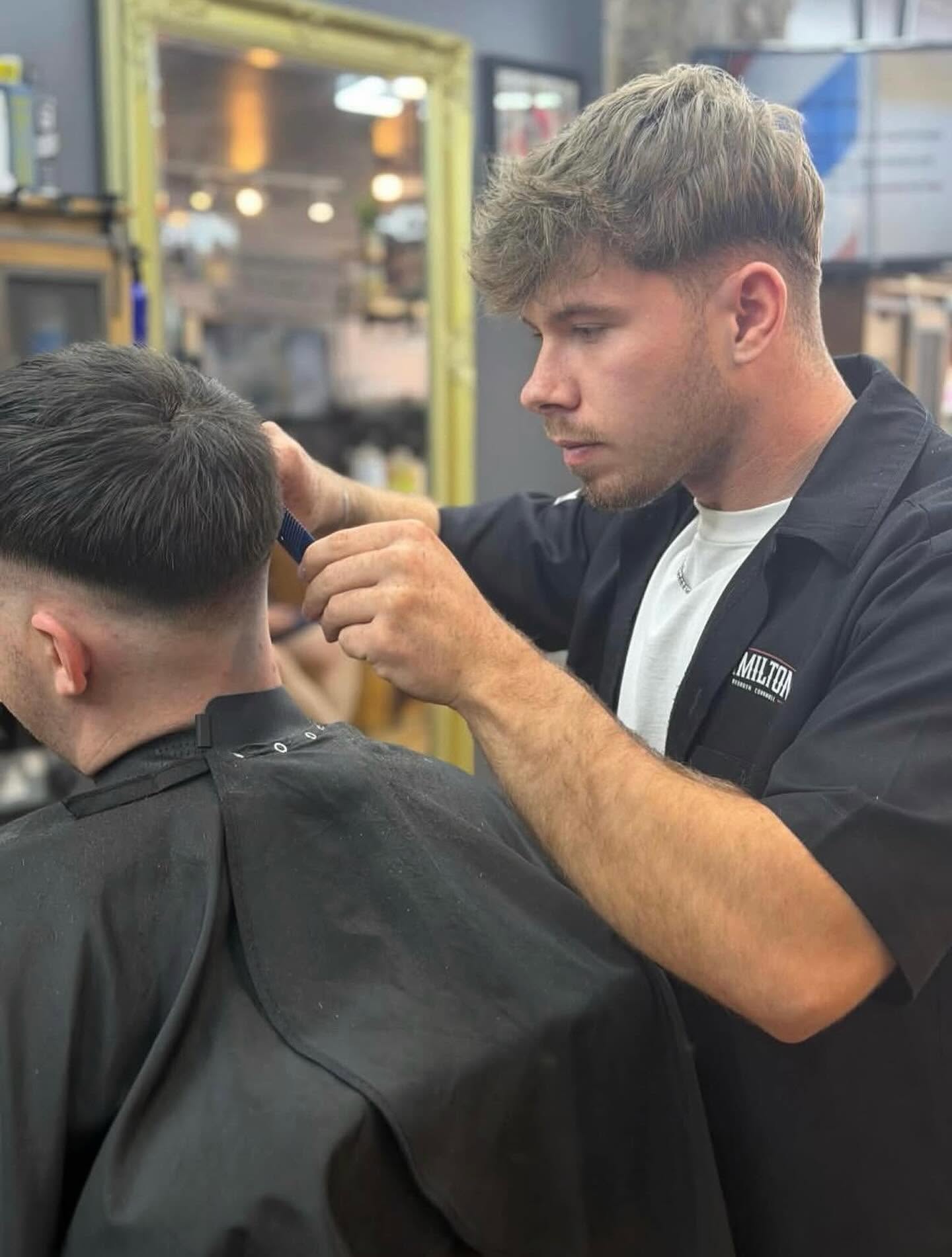 A barber cutting a man's hair in the barbershop