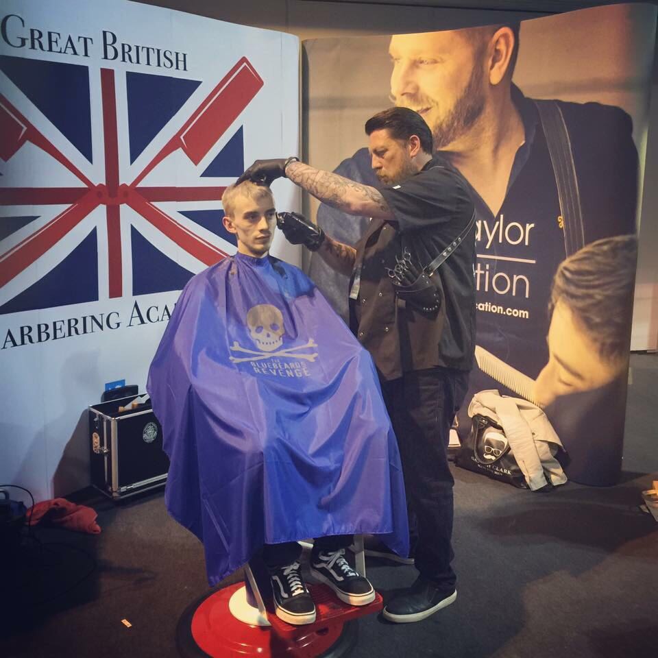 A barbering demonstration on a stage with people watching