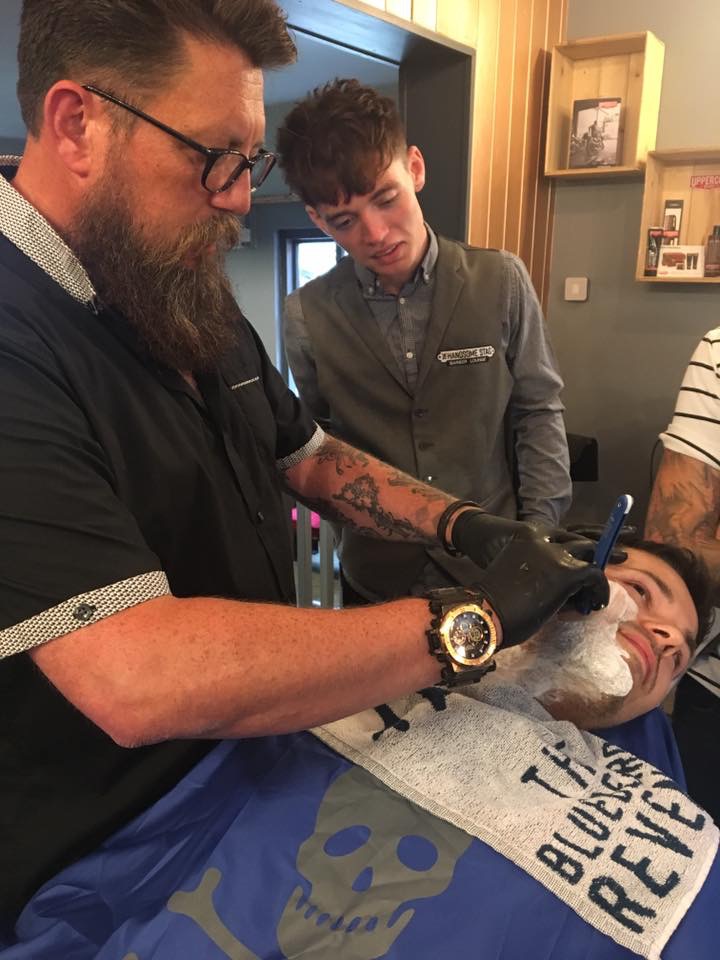 A razor being used on a model's face while another person watches