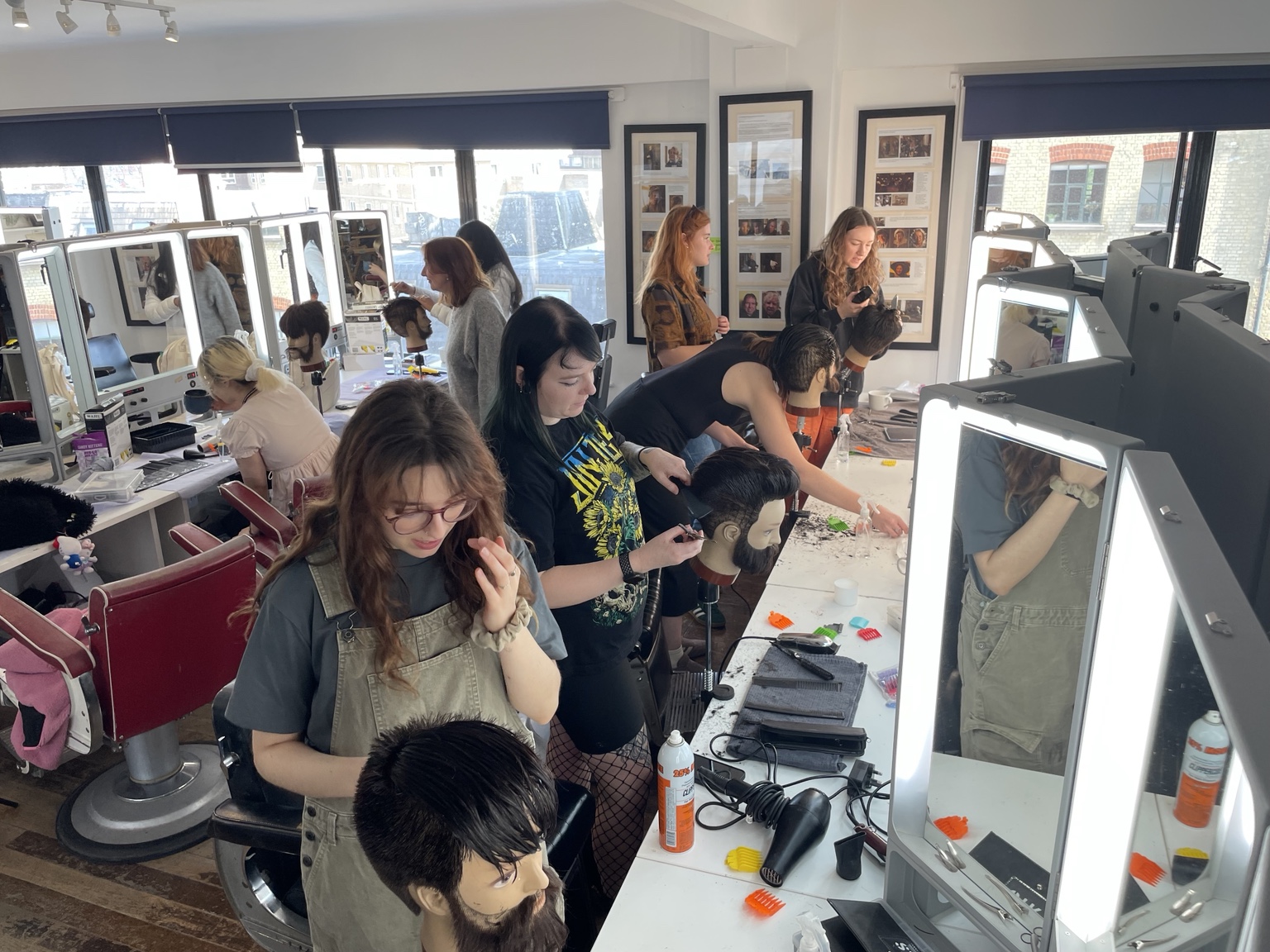 People practising barbering techniques on mannequin heads