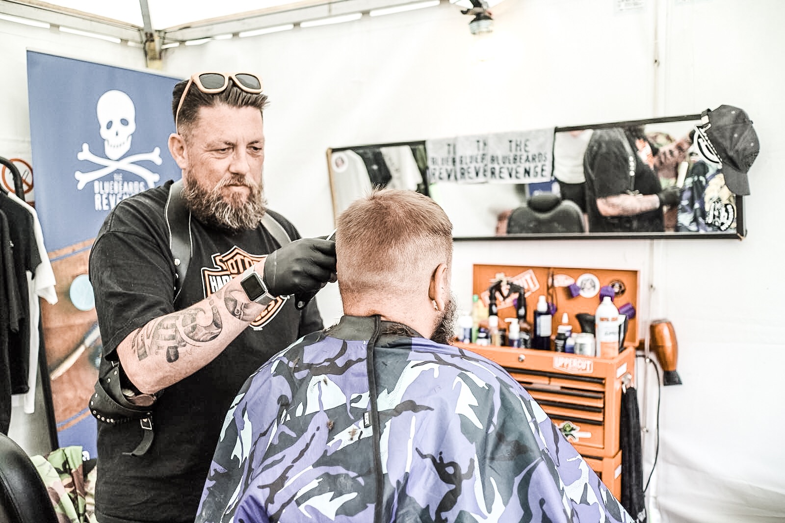A barber cutting hair at an outdoor event stand