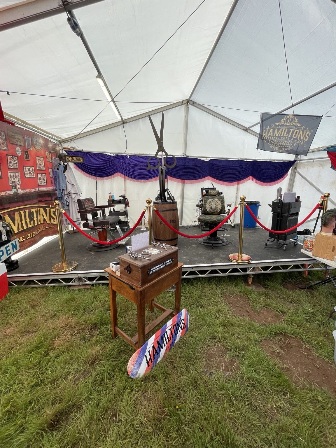 A barbering setup inside a marquee at an outdoor event