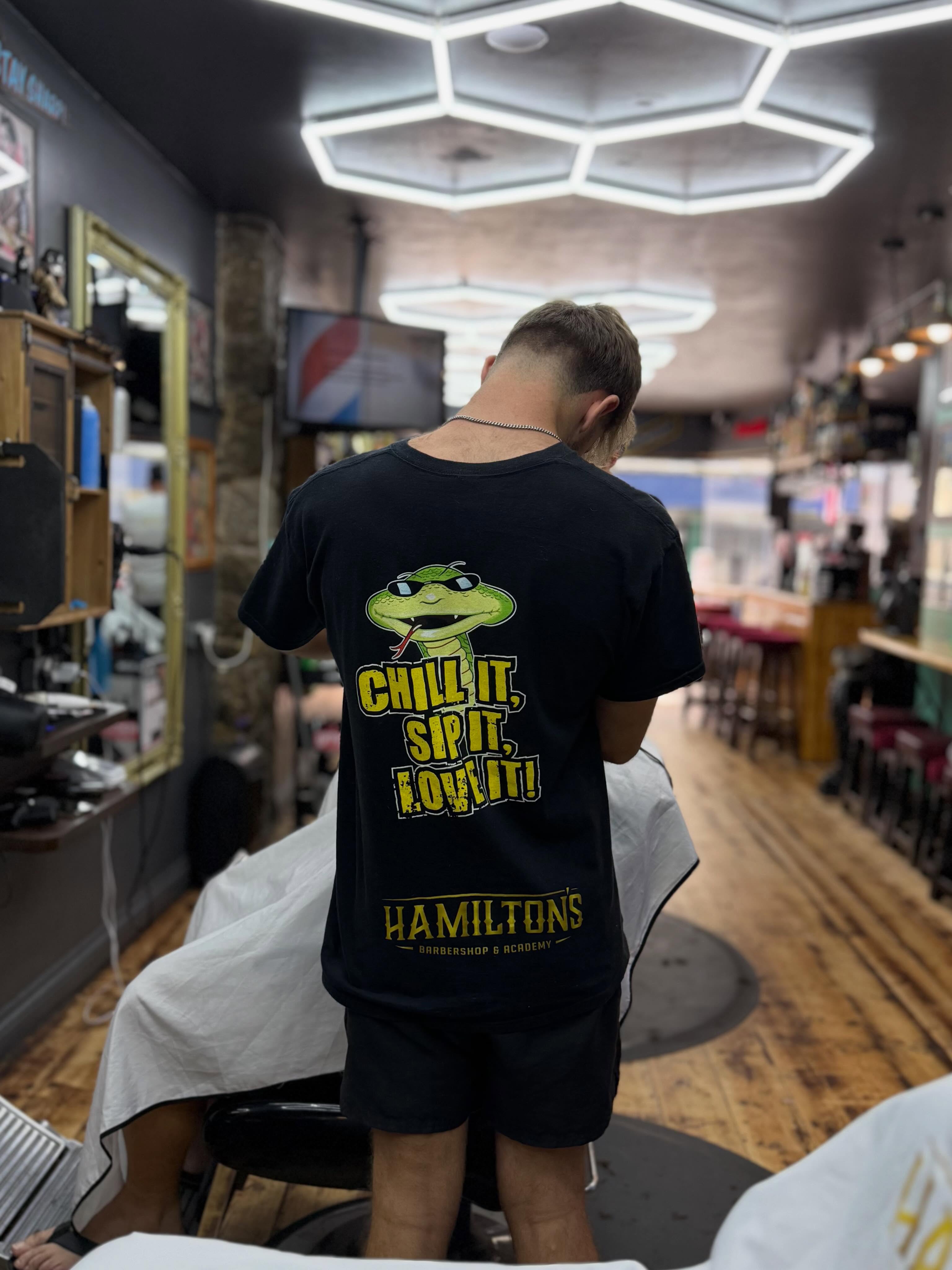 A Hamilton's barber cutting hair beneath the shop's hexagonal lights at 24 Fore Street