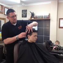A barber cutting a young customer's hair in an early Hamilton's shop